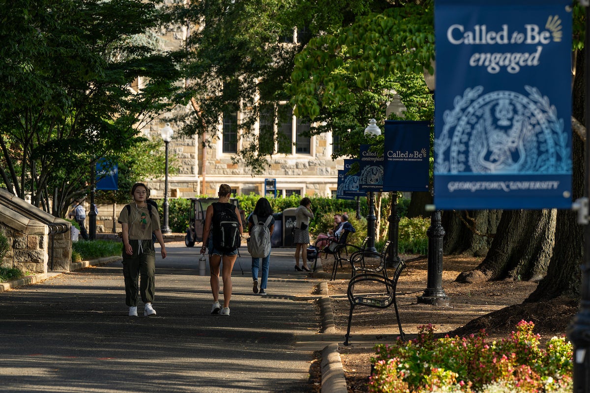 Students walk through Georgetown's campus with the banner "Called to be engaged" showing in the foreground.